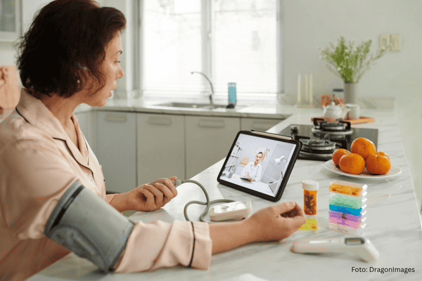 Bestagerin mit Tablettenbox und anderen medizinischen Hilfsmitteln bei der Online-Sprechstunde
