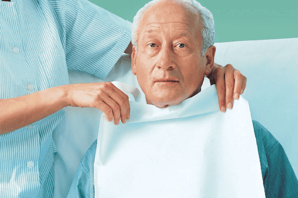 Einweg Esshilfe wird einem Senior von Pflegerin angelegt